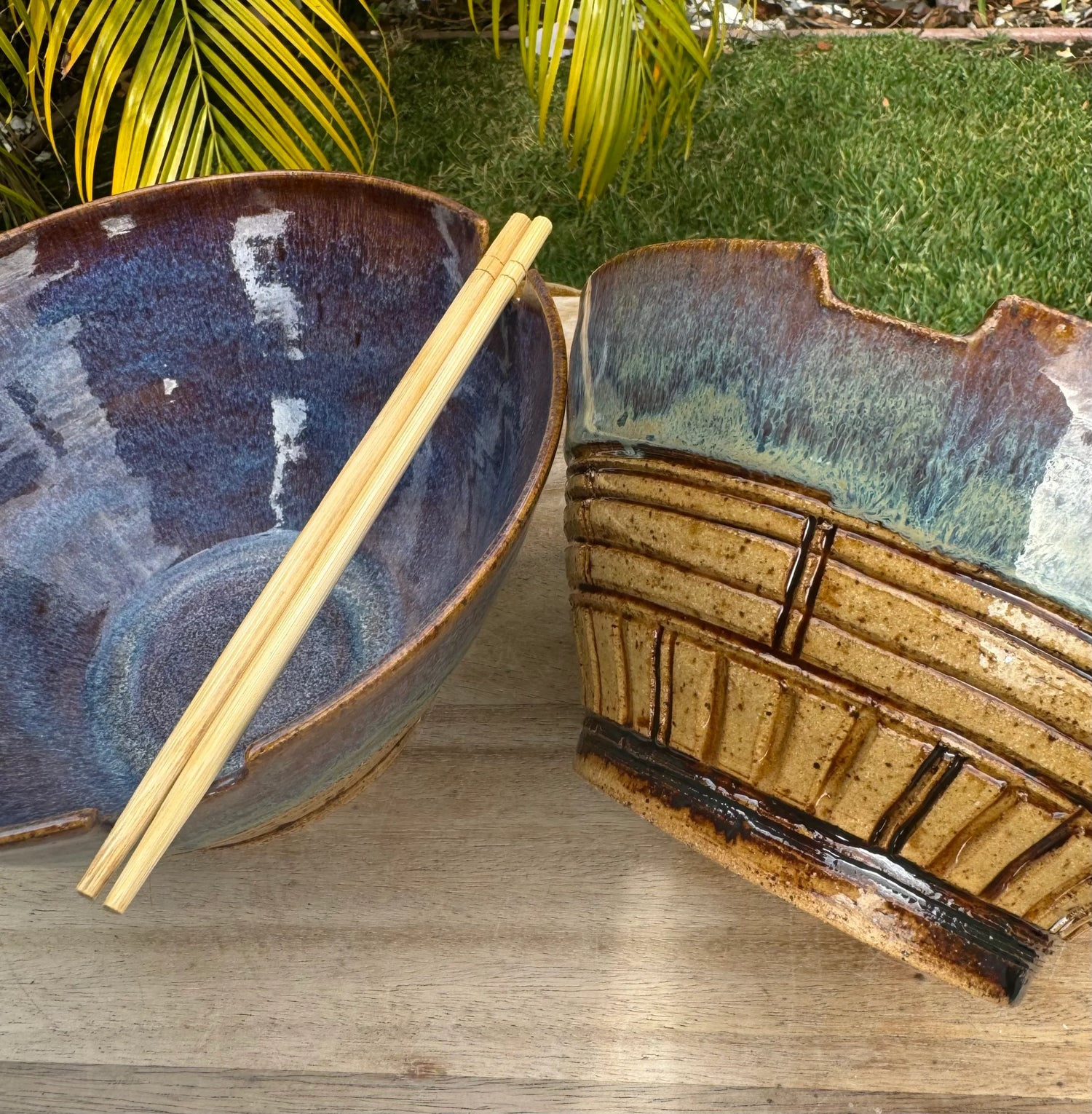 Handmade ceramic ramen bowl set with chopsticks, rustic blue and tan glaze, outdoor setting
