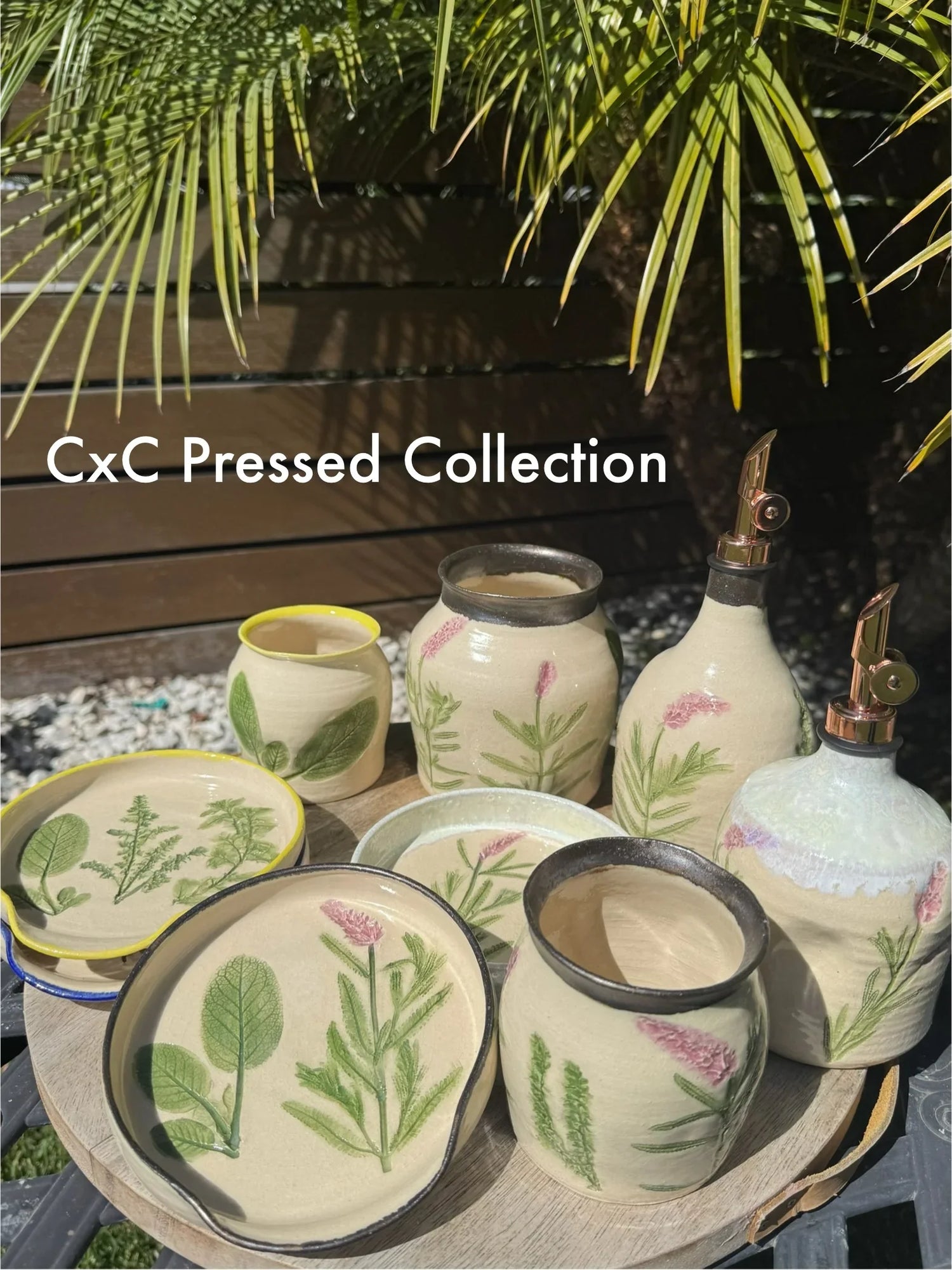 Handmade stoneware pottery with botanical pressed leaf and flower designs, displayed outdoors.