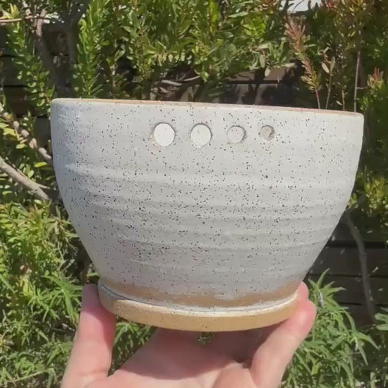 Close up of hand-pierced herb stripper holes on a wheel-thrown white speckle sand ceramic grating bowl - Ceramics By Court