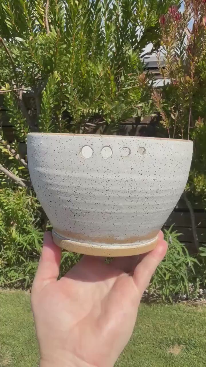 Close up of hand-pierced herb stripper holes on a wheel-thrown white speckle sand ceramic grating bowl - Ceramics By Court